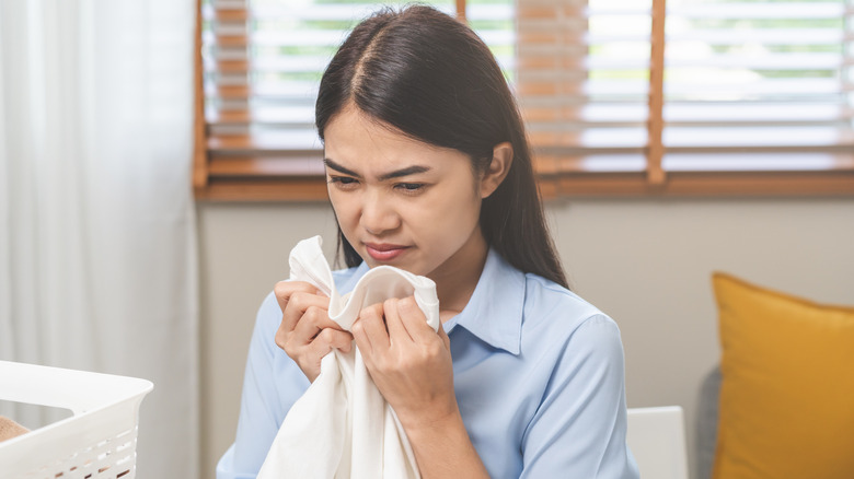 Woman sniffing bad-smelling laundry