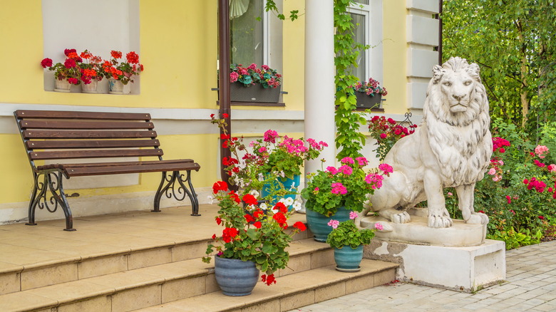 Lion statue in front of a home surrounded by planters filled with flowers