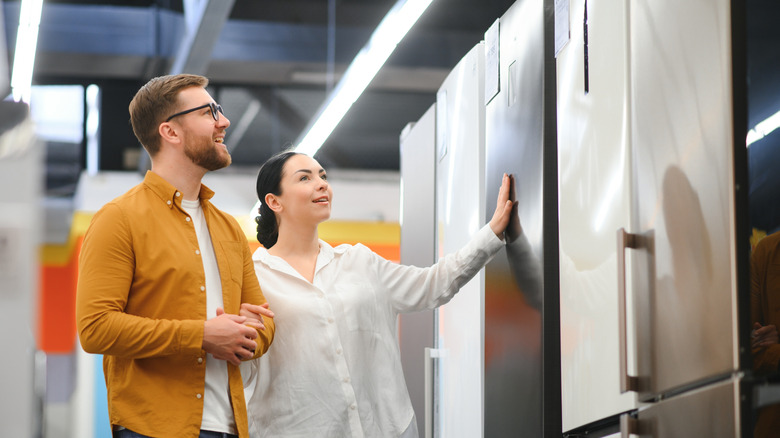 couple at an appliance store looking at different color fridges