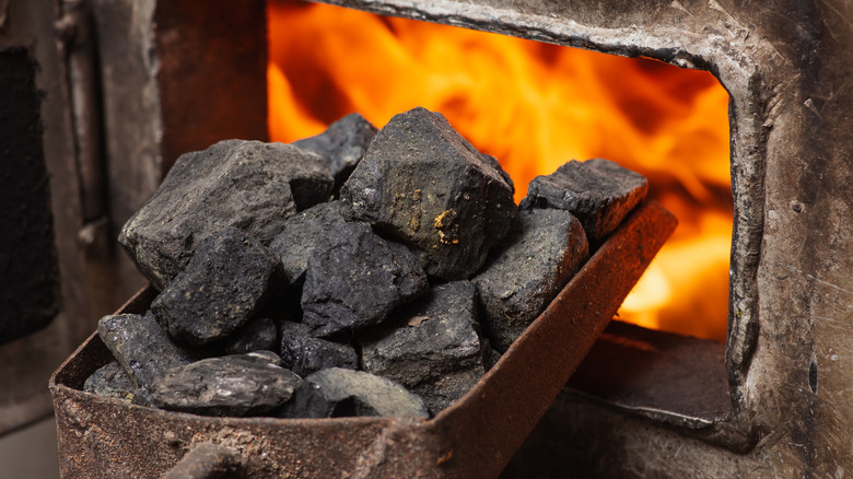 Chunks of coal being shoveled into a furnace