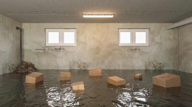 An empty basement has been flooded, with multiple cardboard boxes floating among the debris.