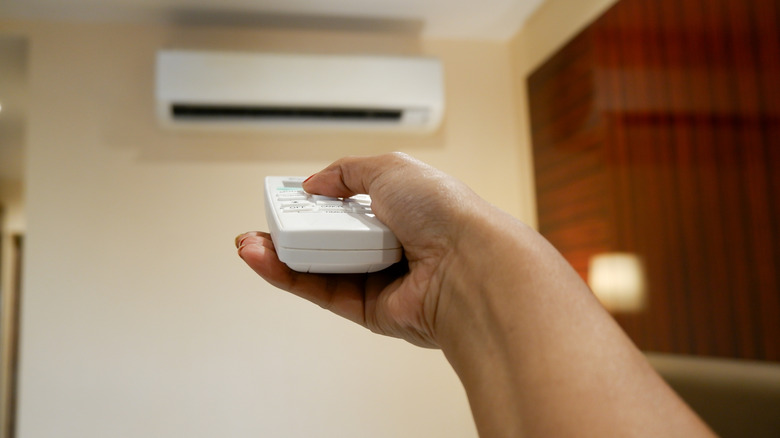 Person points remote at air conditioner