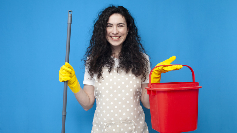 smiling woman holding cleaning supplies