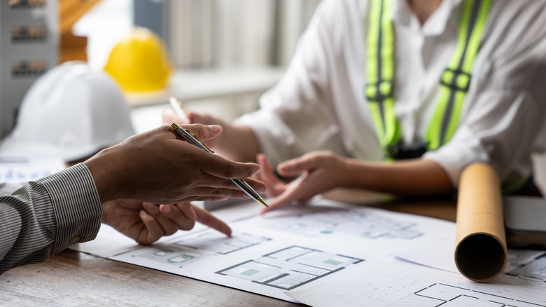 Two people discuss home renovation plans over a blueprint