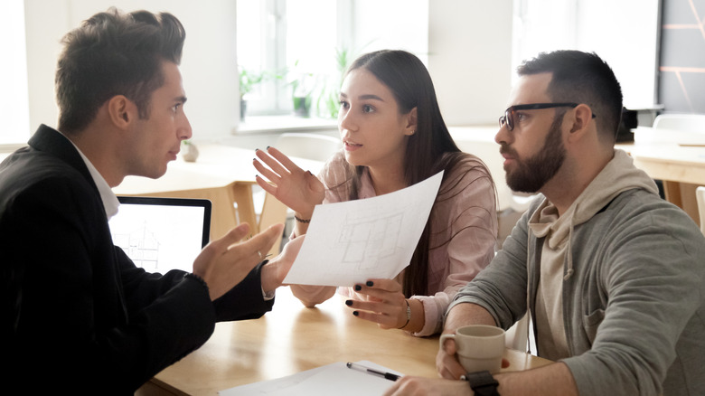 Upset couple talking to a man while looking at paperwork