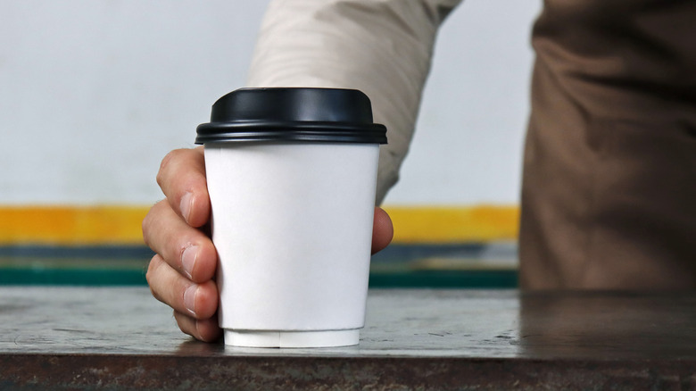 Person holding a takeout coffee cup
