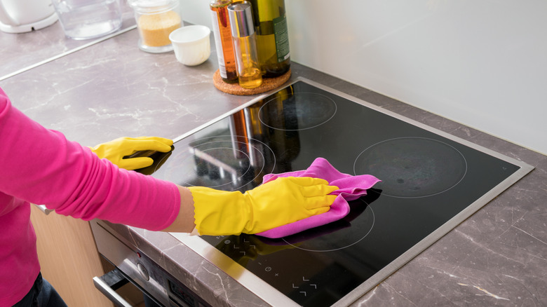 A person cleans a glass stovetop.