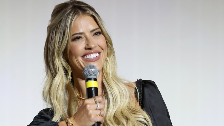 Christina Haack holding a microphone and smiling at the camera