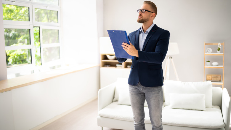 A man inspecting a home and jotting down notes