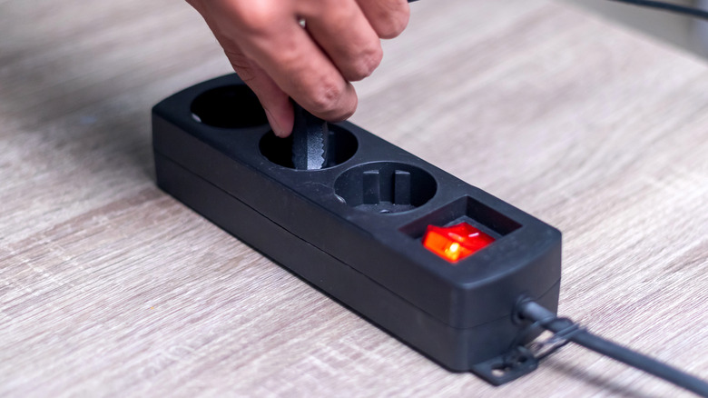 A closeup of a black indoor extension cord with three sockets