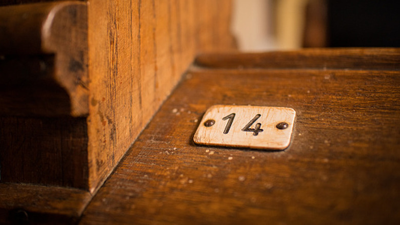 A small plate with a number 14 on it on an old wooden bench