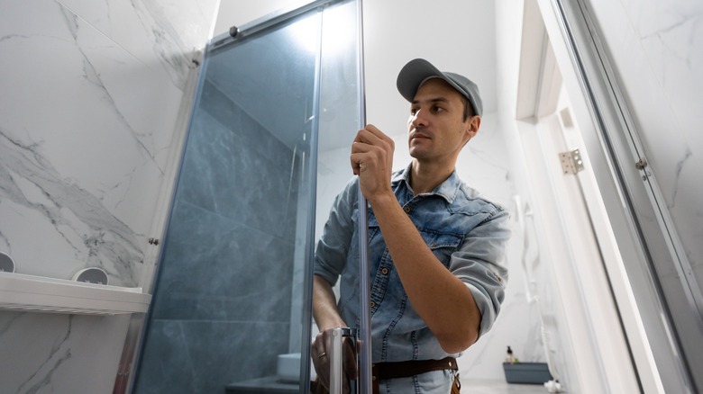 Man installing glass shower door 