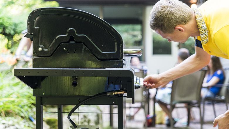 Man turning on the burner of gas grill