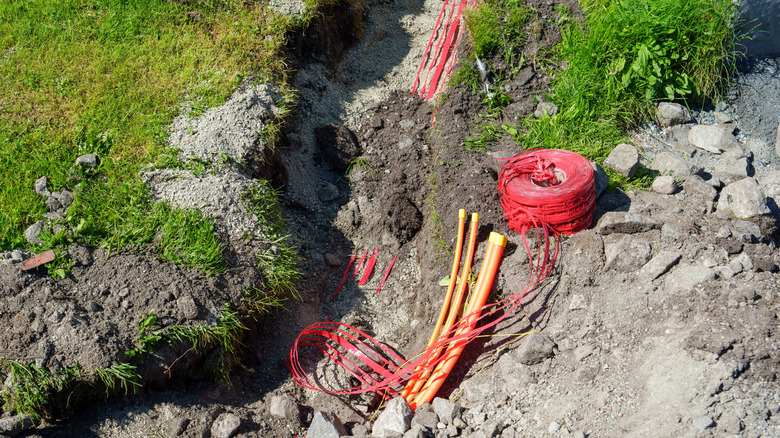 Fiber optic cable being run about a foot underground in a front yard.