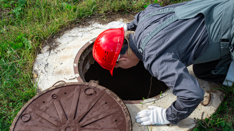 A person inspecting the inside of a septic tank