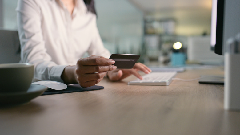 A close-up of a woman's hands while online shopping in an office setting