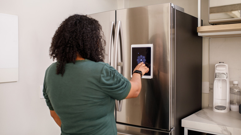 Person pressing button on stainless steel refrigerator