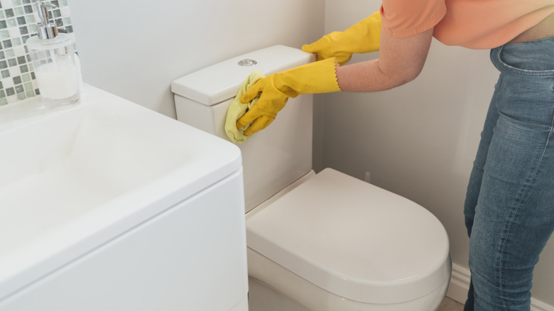 Woman wiping wet toilet