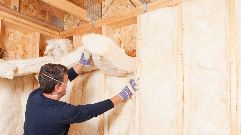 Insulating a standard-framed wall, showing studs that create thermal bridges between one wall and the other