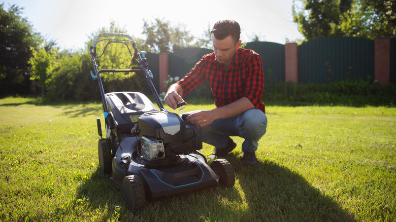 A person performs maintenance on their lawn mower.