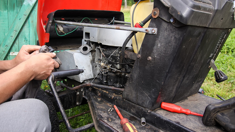 A close up of someone working on a lawn mower engine.