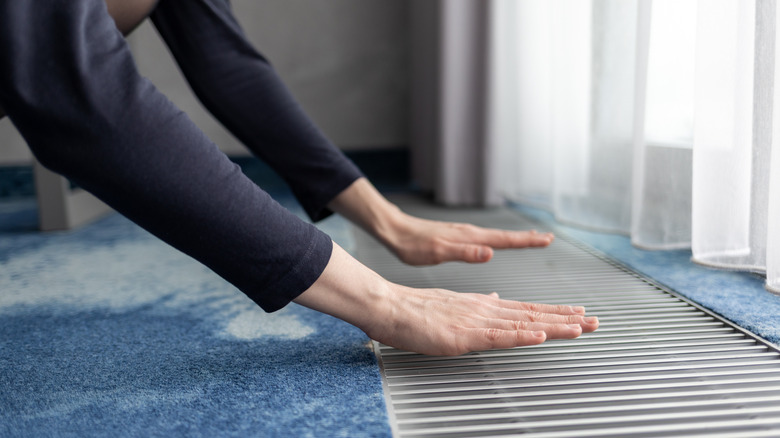 Hands over a floor vent