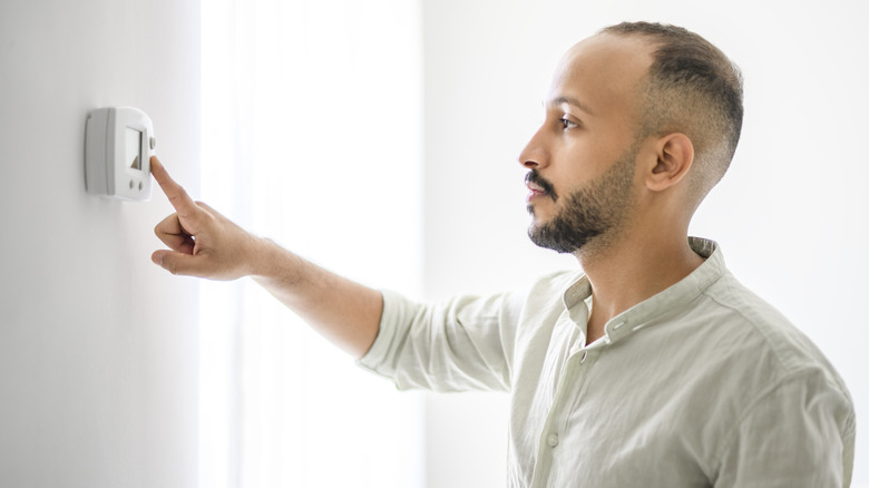 Man adjusting thermostat