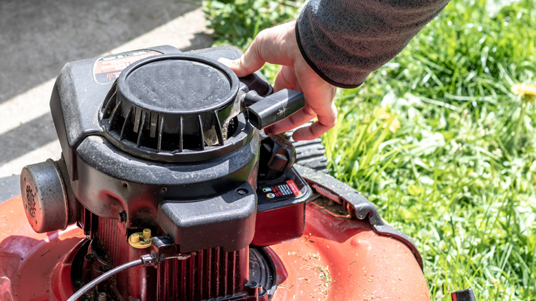 Person's hand pushing the primer bulb on lawn mower