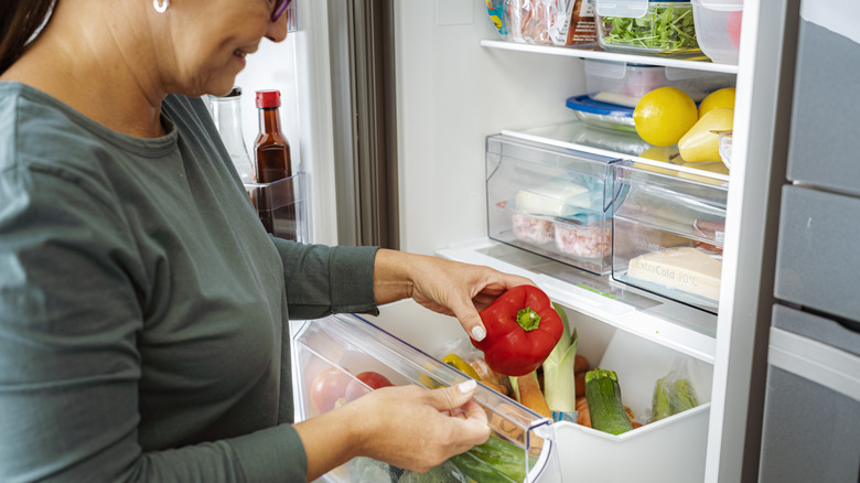 A person putting food away in fridge