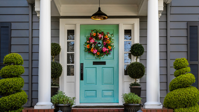 Turquoise front door with topiary