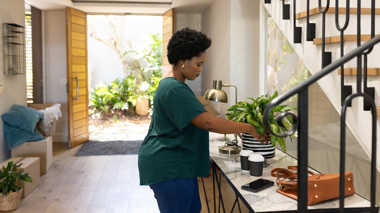 Woman adjusting a potted plant on an entryway console table