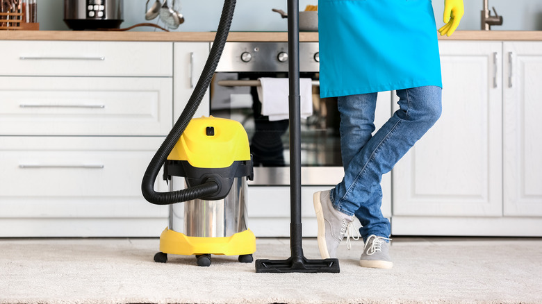 Man holding vacuum in kitchen