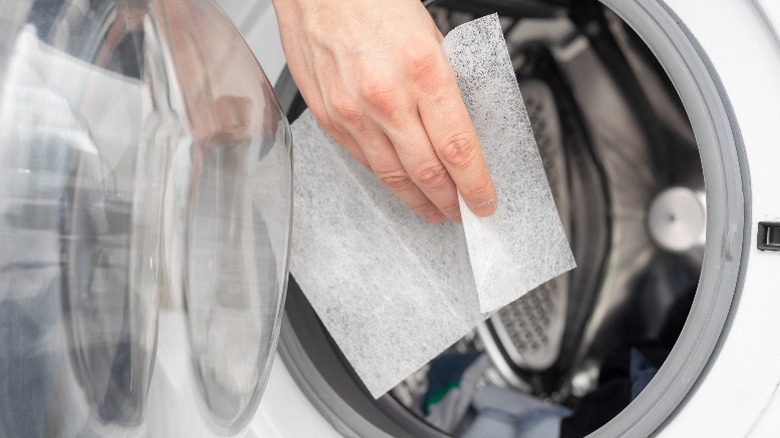 Hand putting dryer sheet in dryer