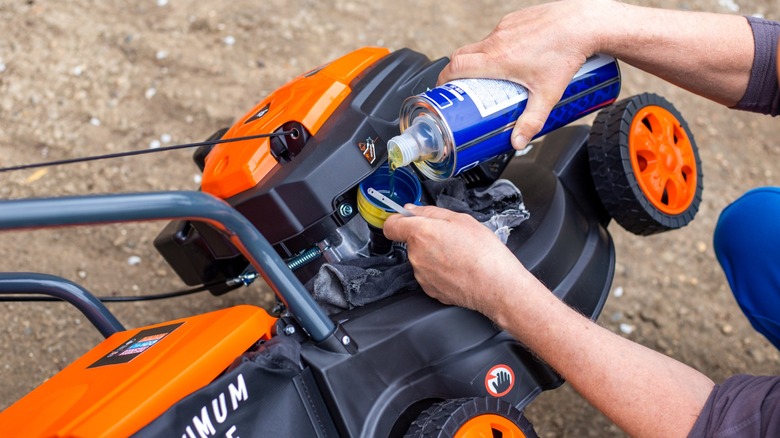 Close up of hand pouring oil into lawn mower