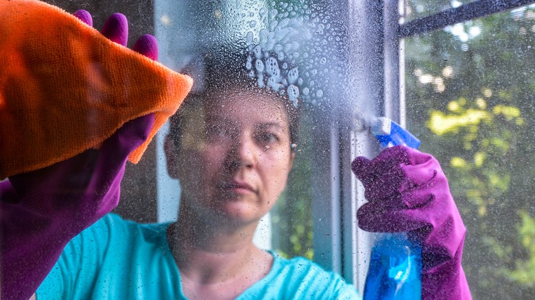 Woman spraying Windex on glass