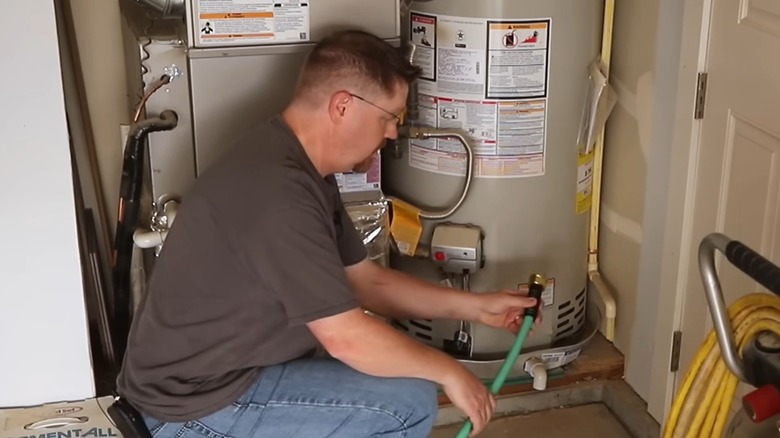 Man connecting a drain hose to a water heater
