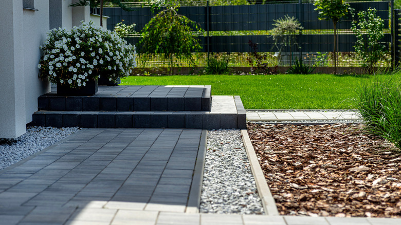 A backyard paver slab patio with steps