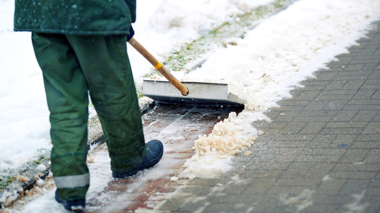 Man removing snow from walkway with metal shovel