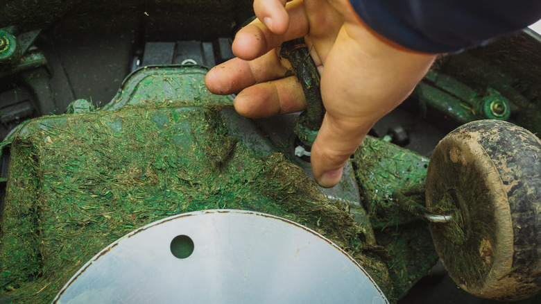 person removing cable from damaged mower underside