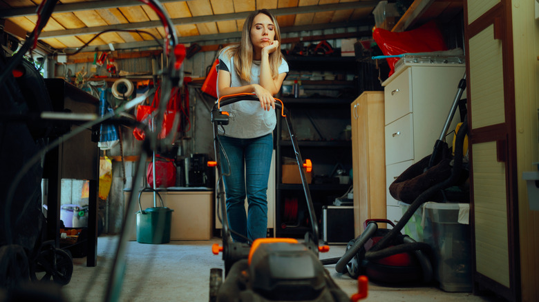 person looking at lawn mower in a garage