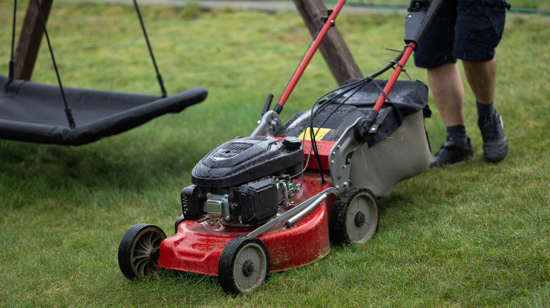 A person mowing the lawn in the rain
