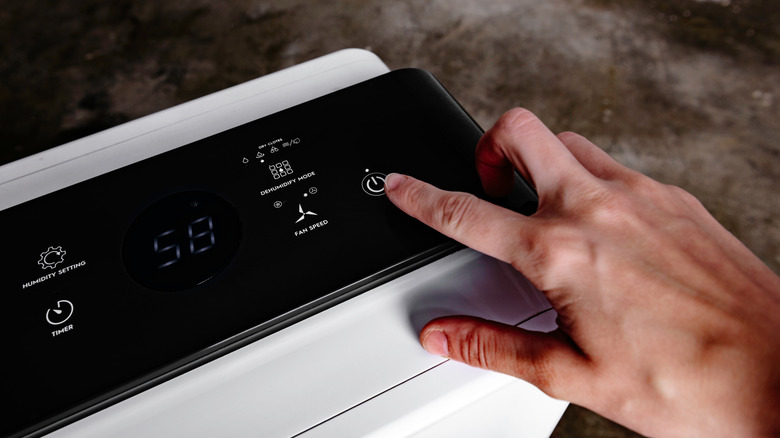 A woman powers on a dehumidifier