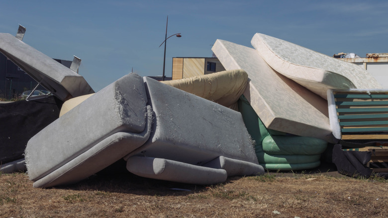 dirty old mattresses and a sofa are dumped into landfill
