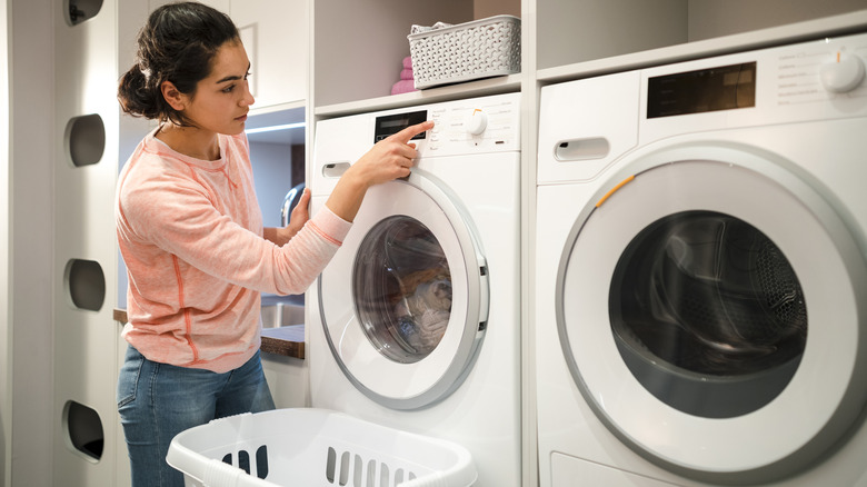 Woman using washer and dryer in a small laundry room