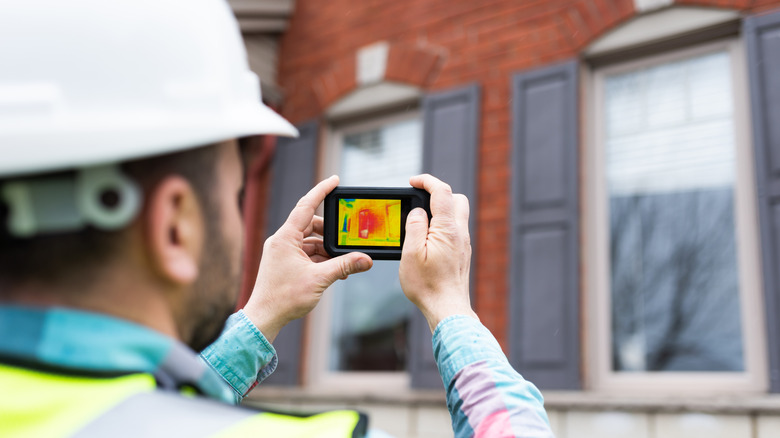 Inspector analyzing heat loss on a home with thermal imaging