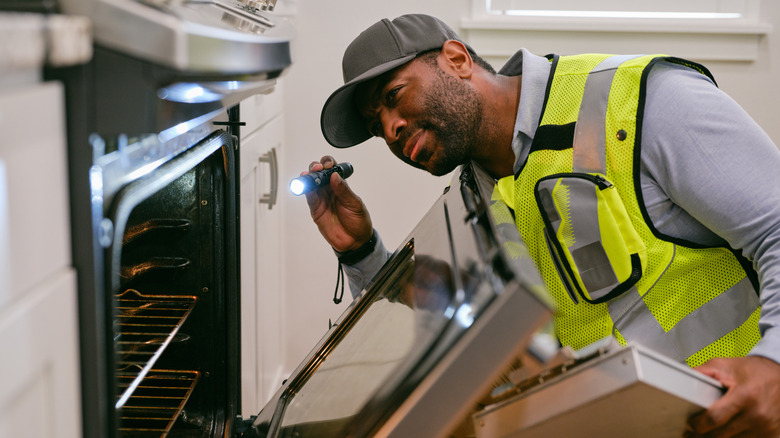 Inspector checking kitchen appliances, looking at oven