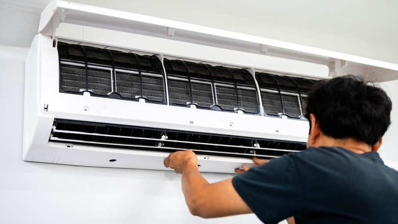 A man services a mini split air conditioner inside of a modern home