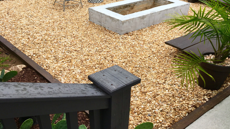 Two outdoors chairs and other furniture on a pea-gravel patio