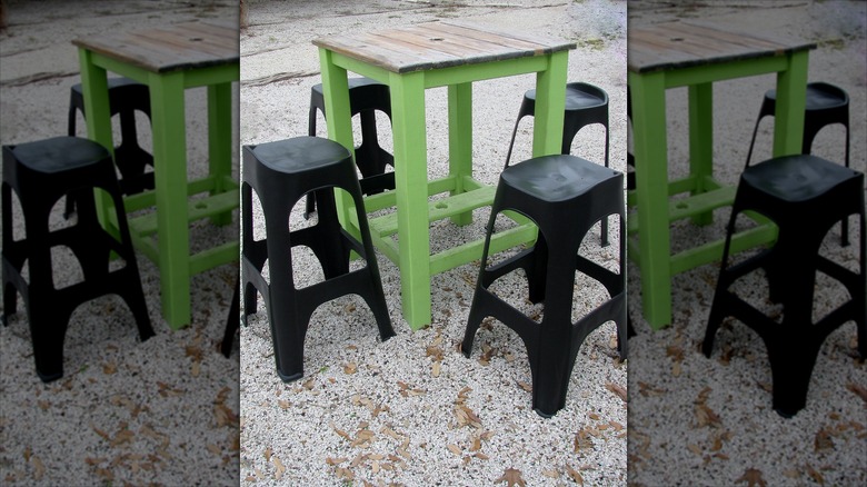 a small table and plastic stools on a pea gravel patio