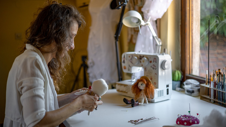 A woman crafting in a room with a large window.